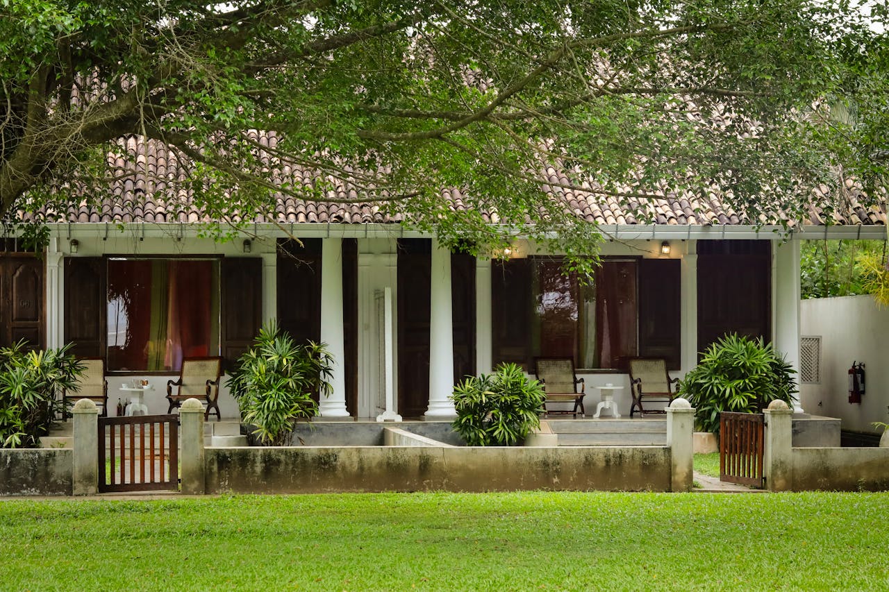 Colonial-style house with a lush garden and picturesque front porch surrounded by greenery.